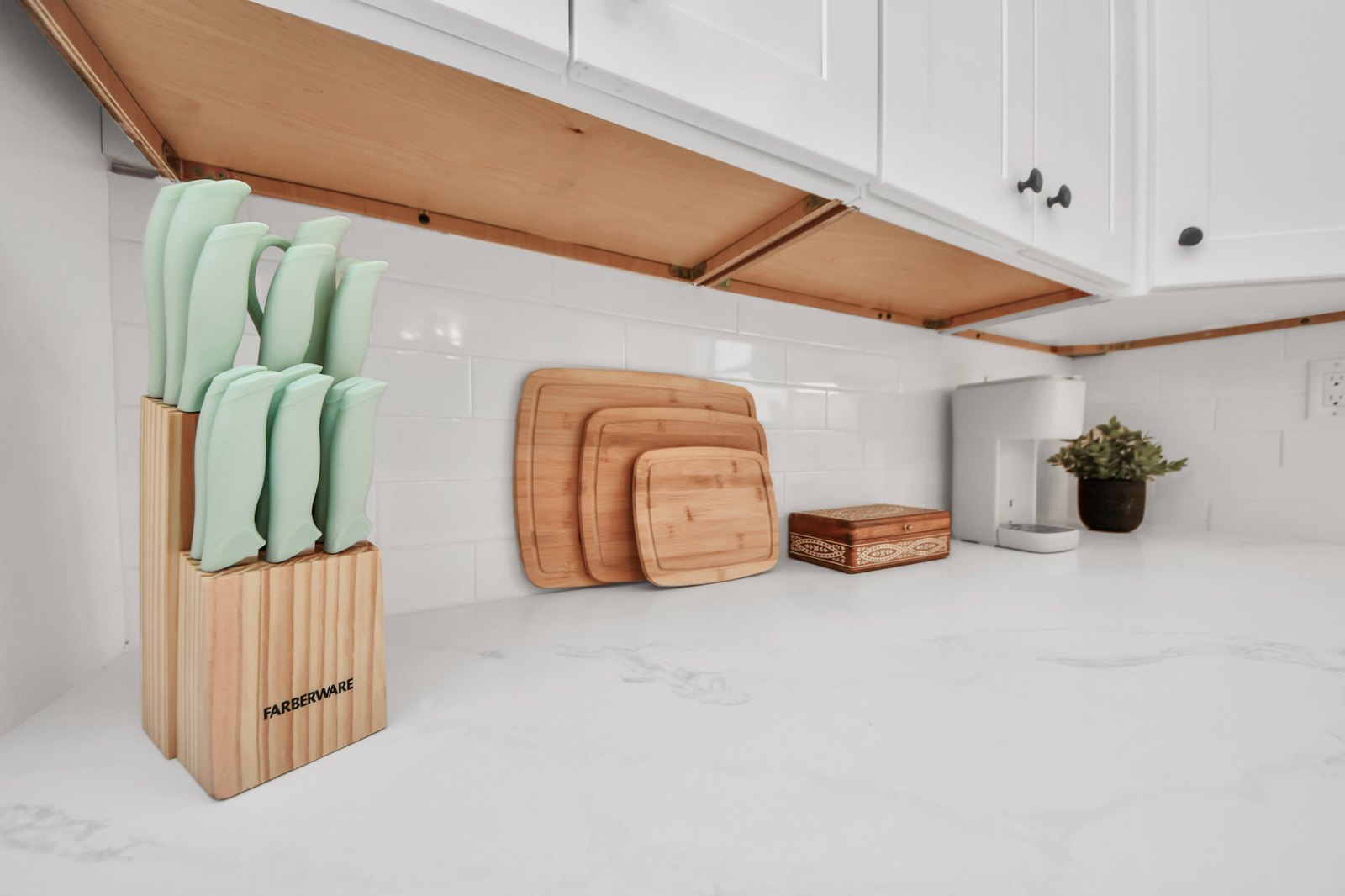 Wooden knife block and a set of bamboo cutting boards on the quartz counter