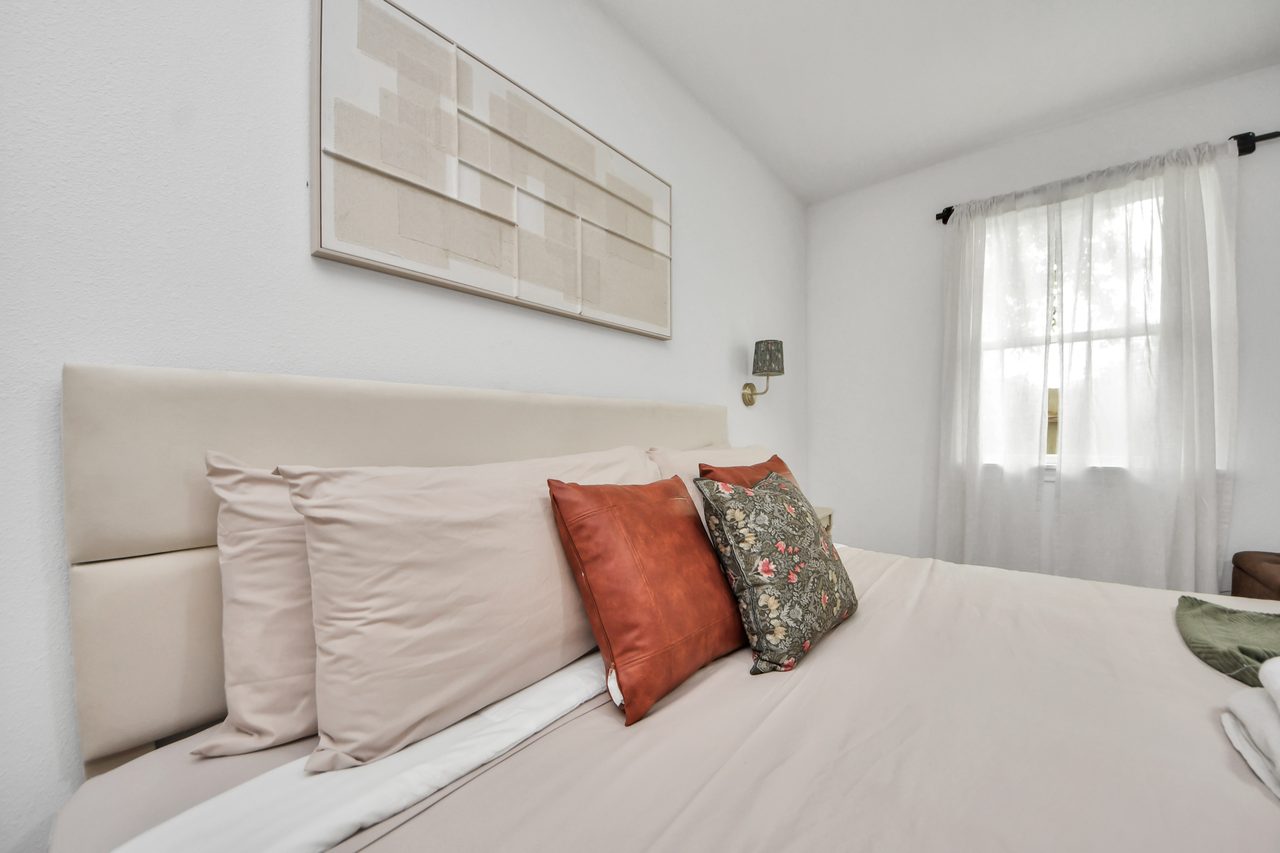 Bedroom with cream bedding and rust pillows