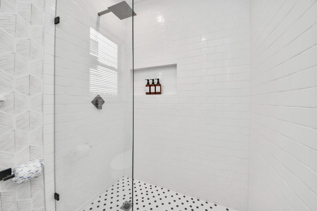 Glass walk-in shower with tiled walls and niche