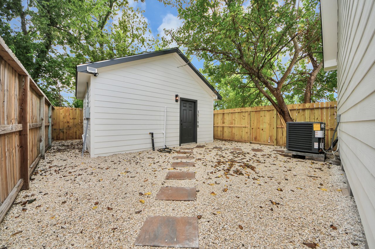 Fenced backyard with gravel and mature tree
